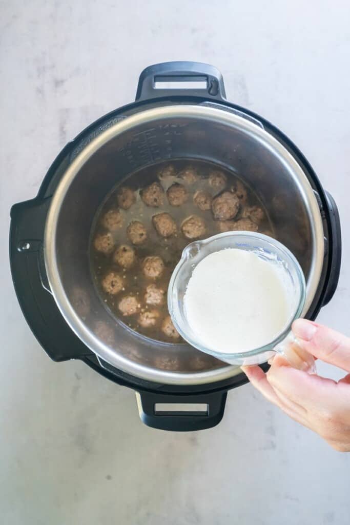 Adding cream and cornstarch to meatballs in an Instant Pot.