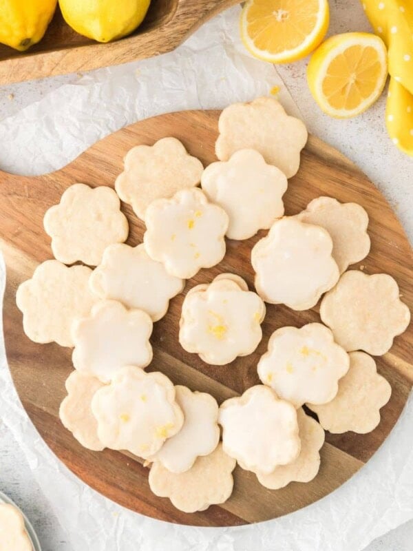 A batch of glazed lemon shortbread cookies on a wooden serving platter.