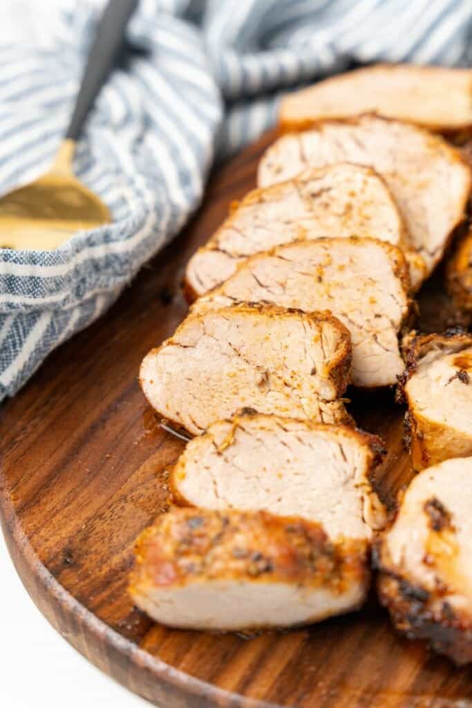 Closeup view of pork tenderloin cut into slice on a cutting board.