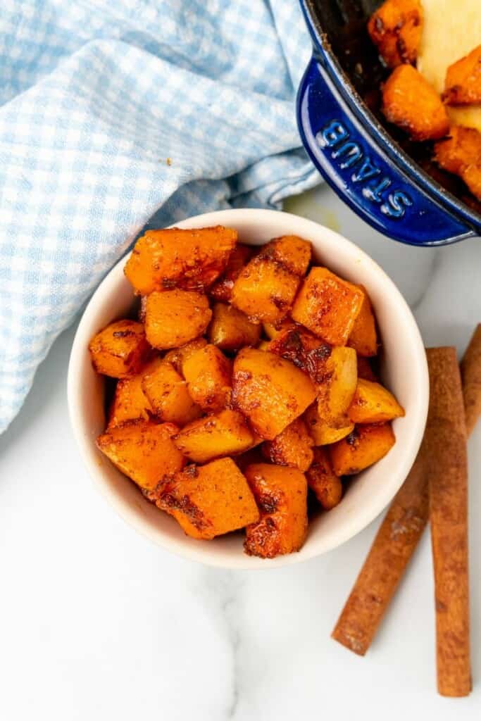 Overhead view of a bowl of pan fried butternut squash in an off-white bowl.