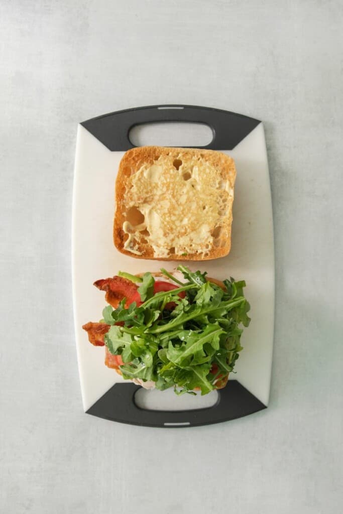 Topping this turkey sandwich with arugula.