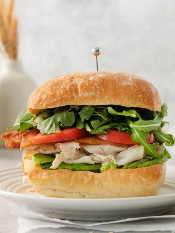 A turkey bacon avocado sandwich on a white plate.