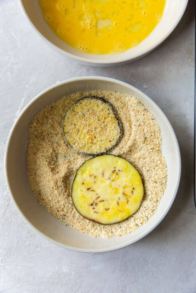 Breading the eggplant in breadcrumbs after it's been coated in egg.