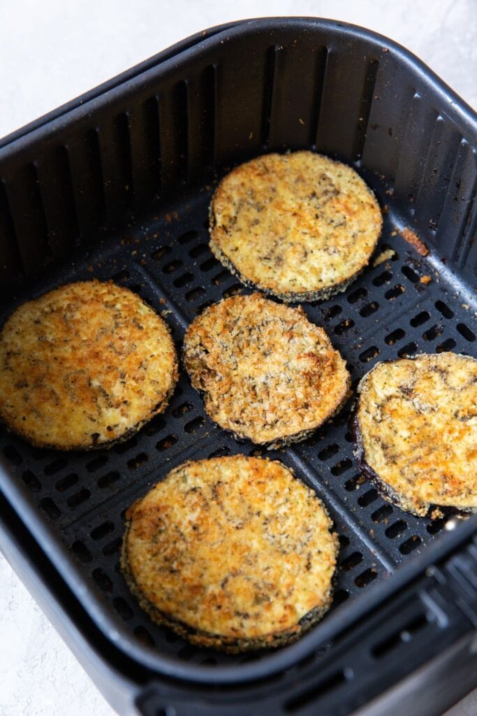 Cooked eggplant parmesan in an air fryer basket.