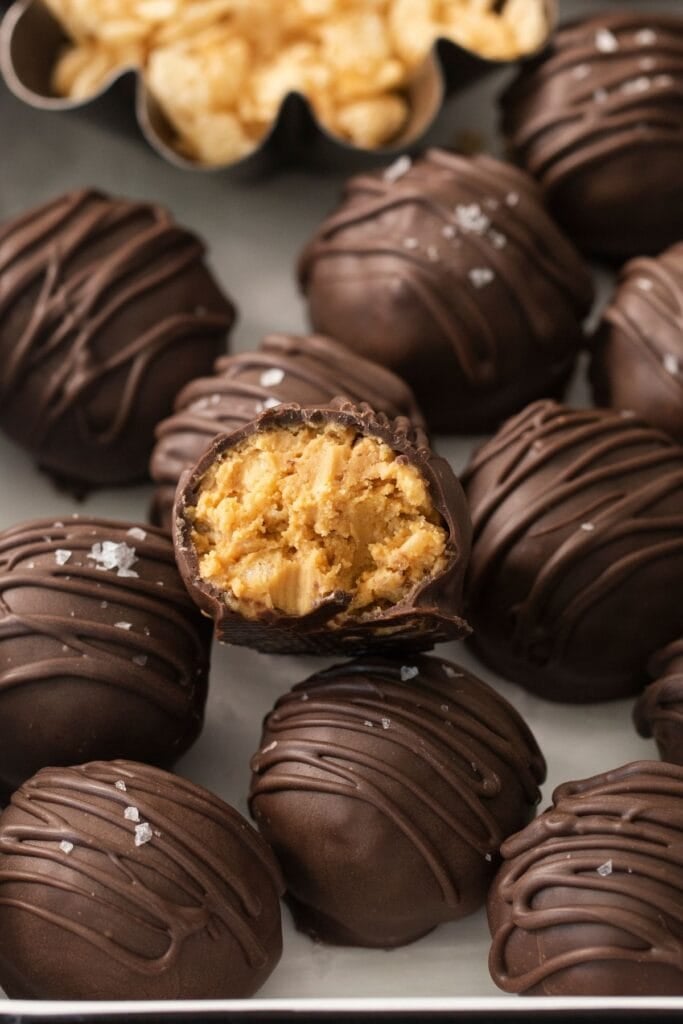 Chocolate peanut butter balls with rice krispies with one with a bite taken out so you can see the inside.