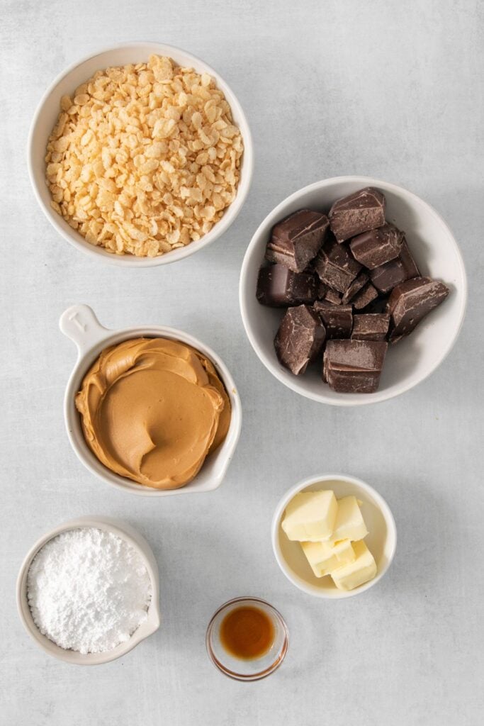 Ingredients needed to make peanut butter balls with rice krispies: peanut butter, butter, vanilla extract, powdered sugar, rice krispies, and chocolate candy coating.