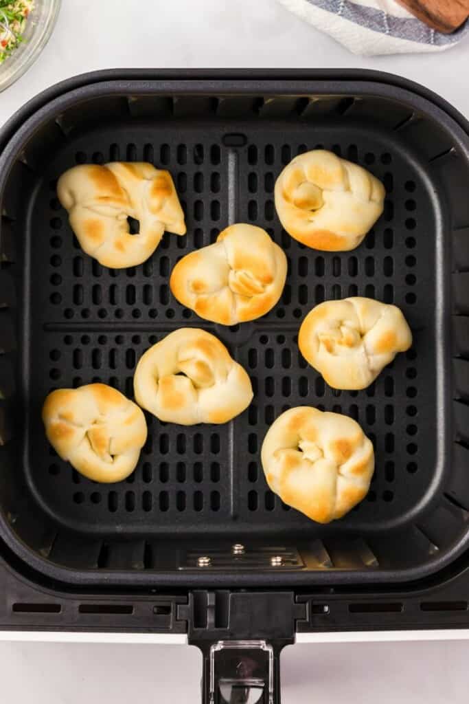 Garlic knots resting in a black air fryer basket.
