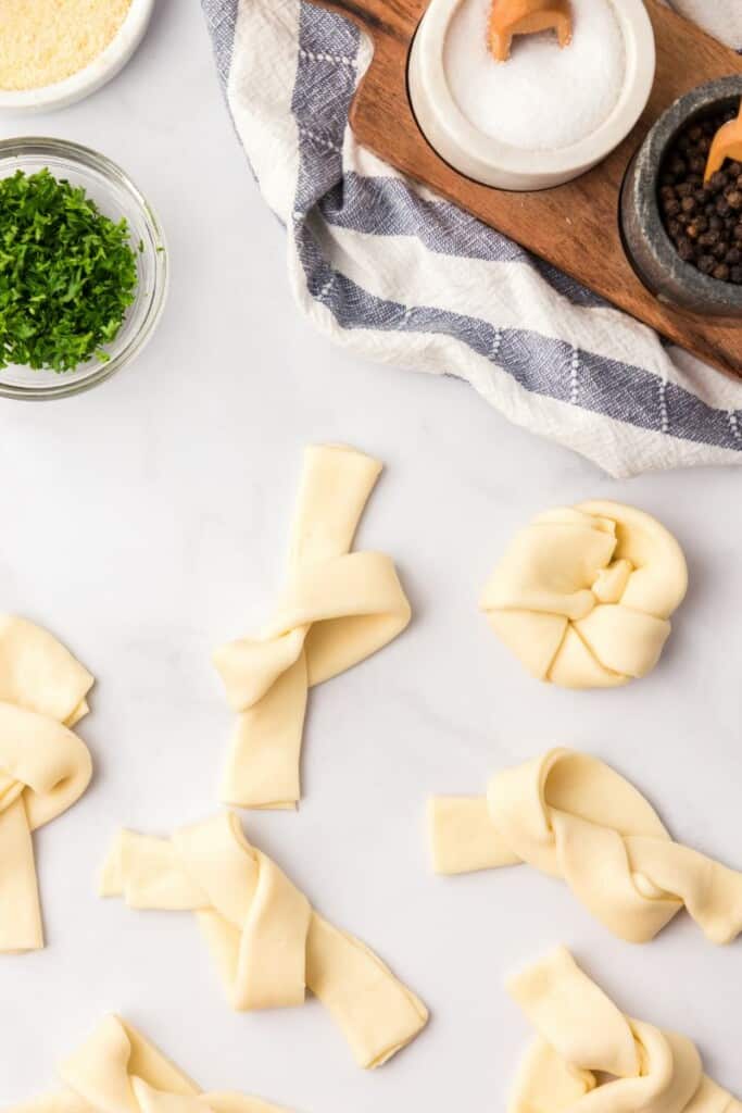 Folding dough slices into knot shapes.