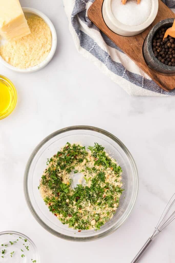 Mixing seasonings and spices in a clear small bowl.