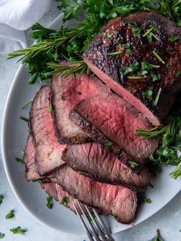 Overhead view of air fryer roast beef half sliced on a serving plate.