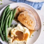 Pork Loin with gravy on a plate with mashed potatoes and green beans.
