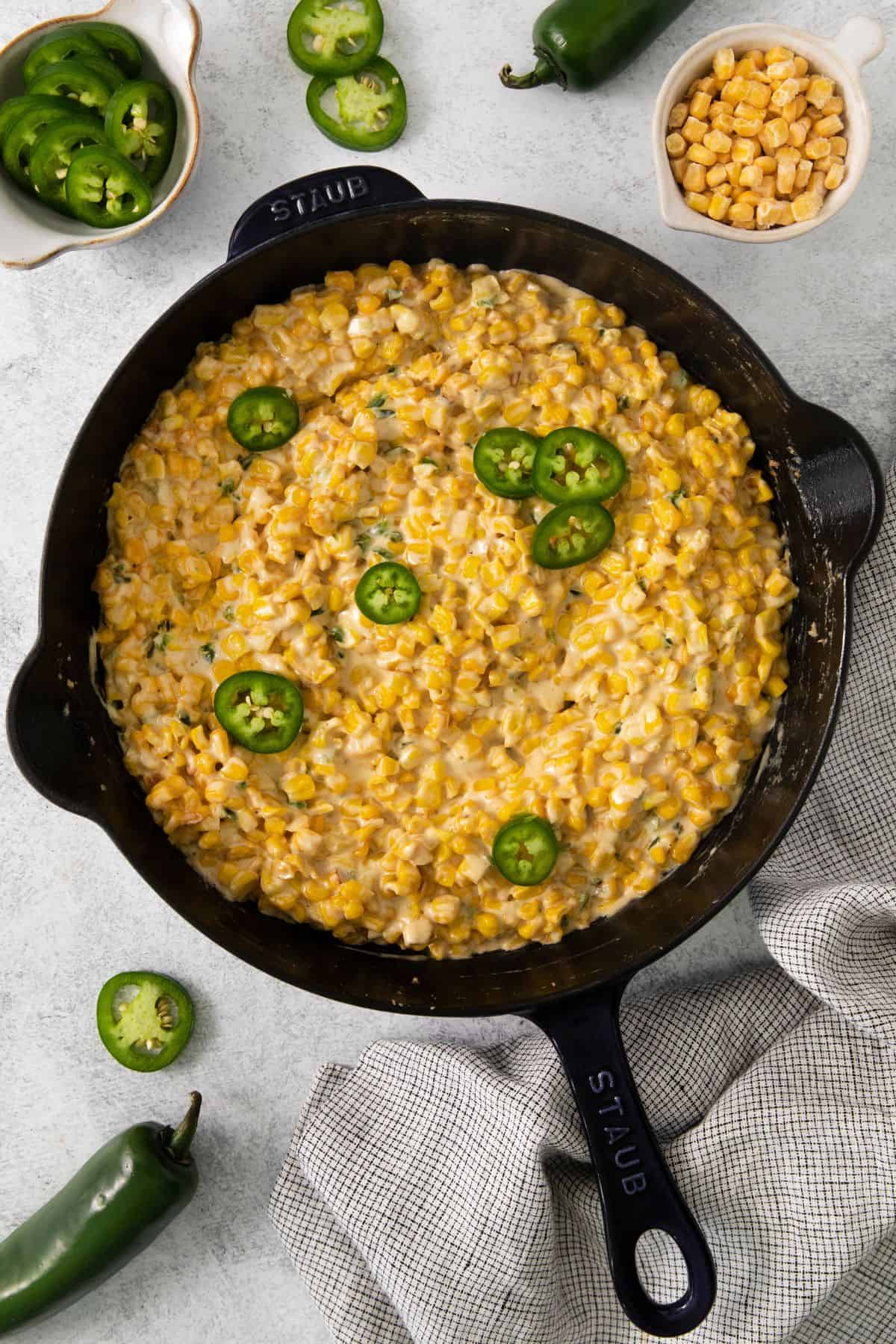 Spicy corn in a skillet with jalapeno slices on top.