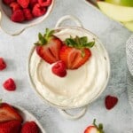 A bowl of marshmallow dip for fruit topped with strawberries.