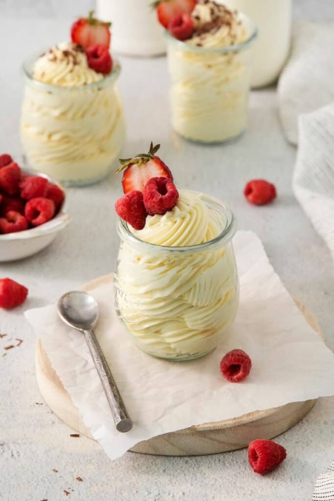 Three dessert serving dishes containing vanilla mousse topped with fresh strawberries.