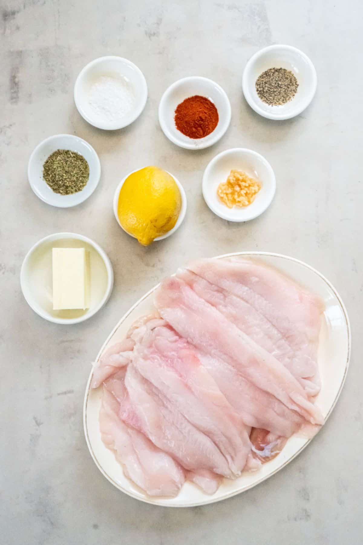 Ingredients needed to make air fryer flounder: flounder fillets, salt, pepper, butter, lemon juice, garlic, paprika, and italian seasoning.