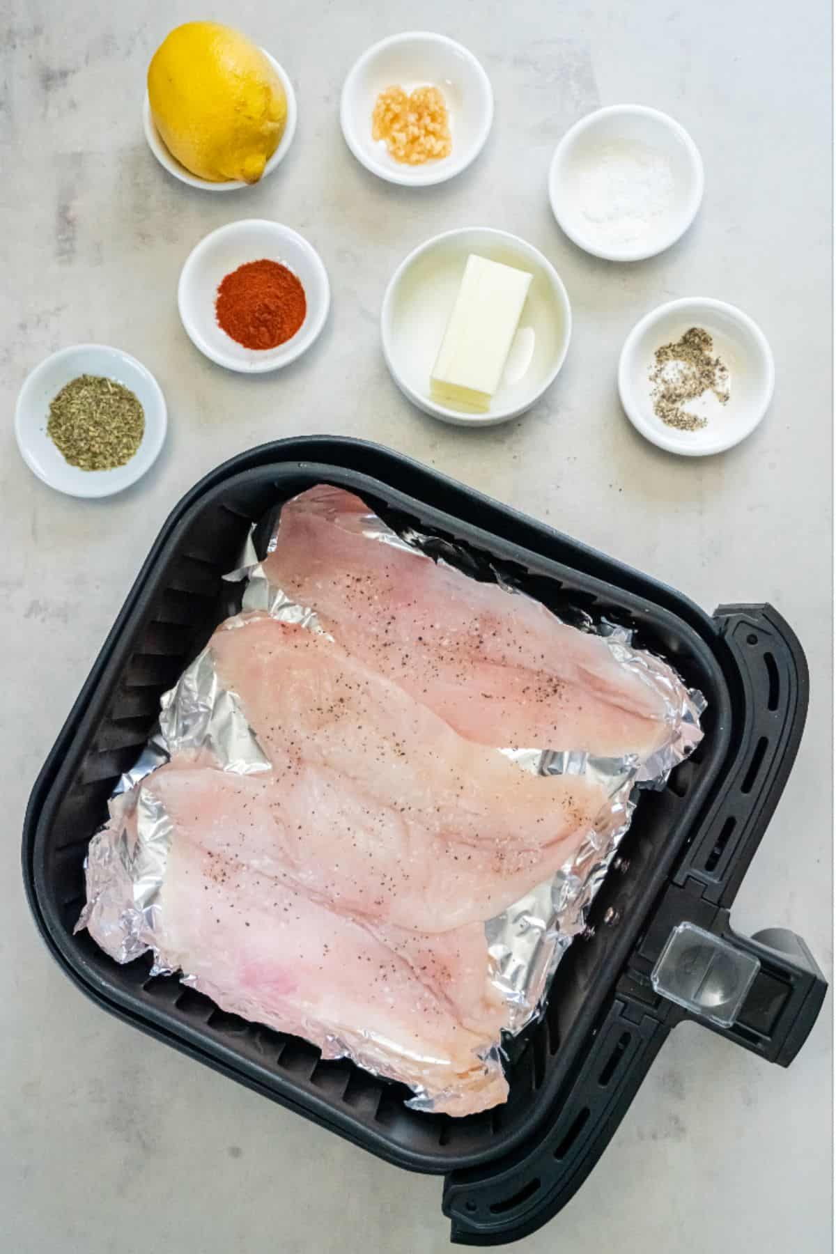 Raw flounder in the air fryer basket about to be cooked.