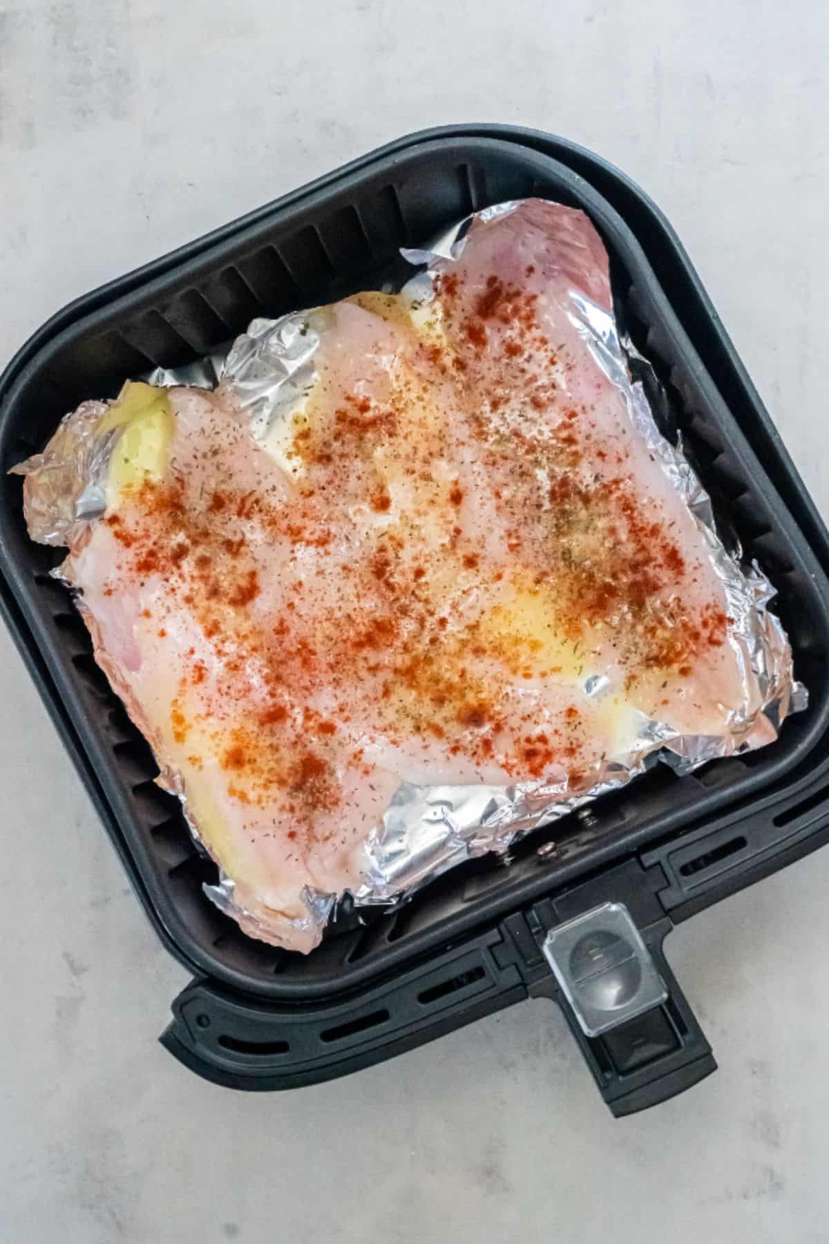 Raw flounder fillets in the air fryer that have been seasoned.