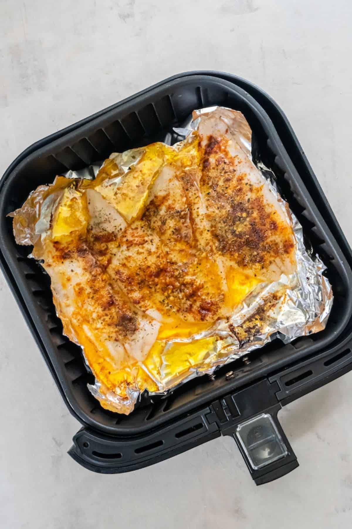 Cooked air fryer flounder inside an air fryer basket.