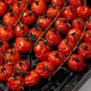 Close up of roasted tomatoes in an air fryer basket.