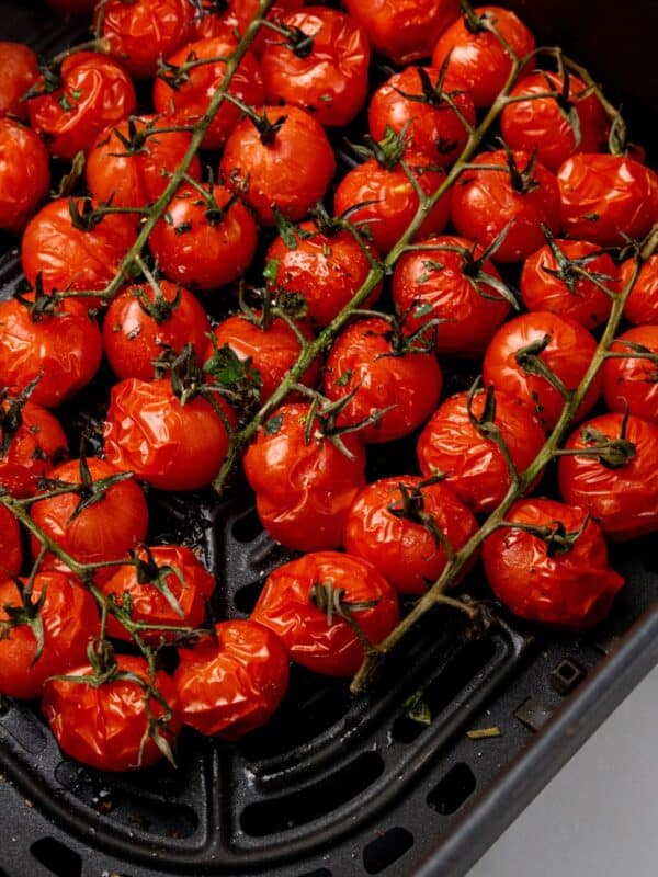 Close up of roasted tomatoes in an air fryer basket.