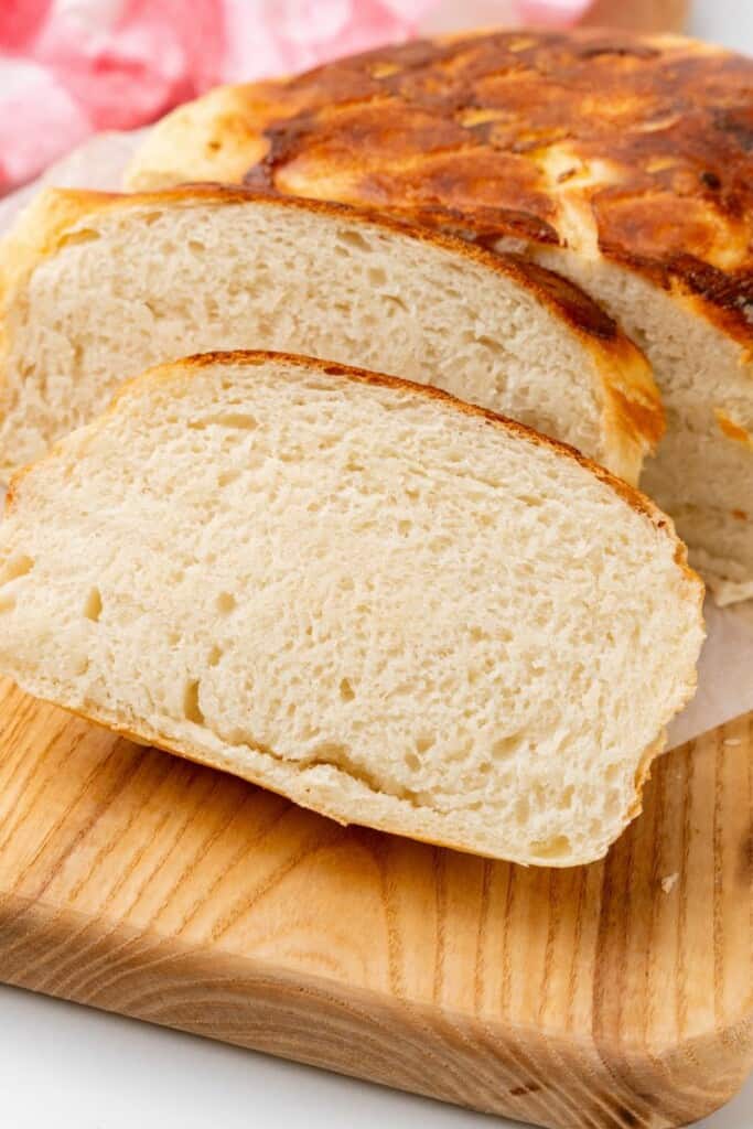 Homemade bread cut into slices on a wooden cutting board.
