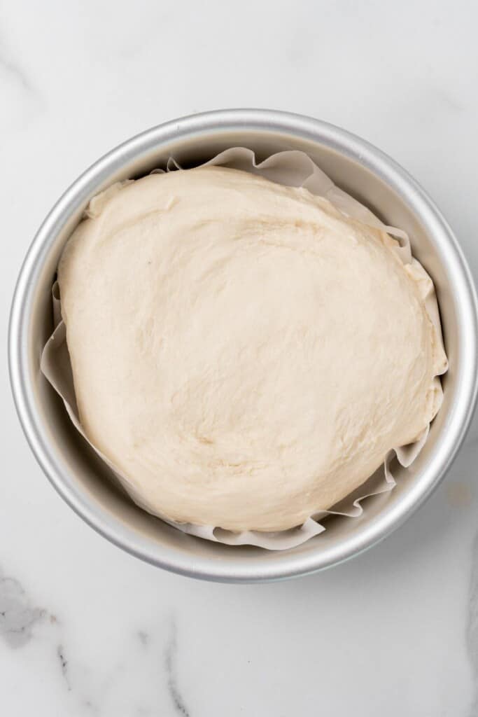 Homemade bread dough continuing to rise in mixing bowl.
