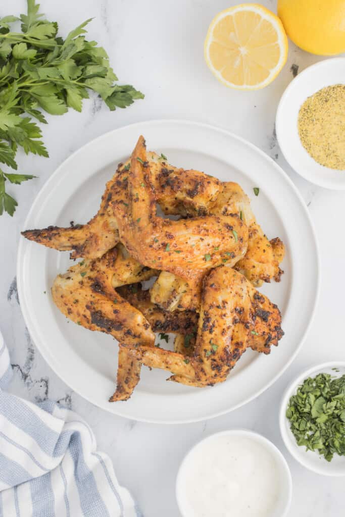 Seasoned whole chicken wings on a white plate.