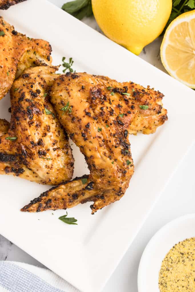 Close up view of a seasoned chicken wing on a serving platter.