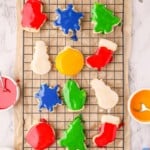 Twelve decorated christmas sugar cookies on a cooling rack.