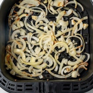 Air fried onions in an air fryer basket.