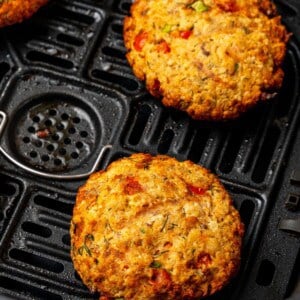 Close up of salmon patties in air fryer basket that are cooked.