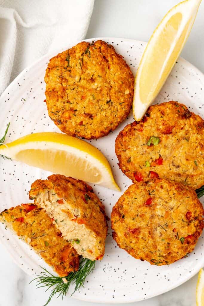 air fryer salmon patties on a plate with lemon wedges.