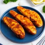 Three air fryer halibut fillets on a blue plate.