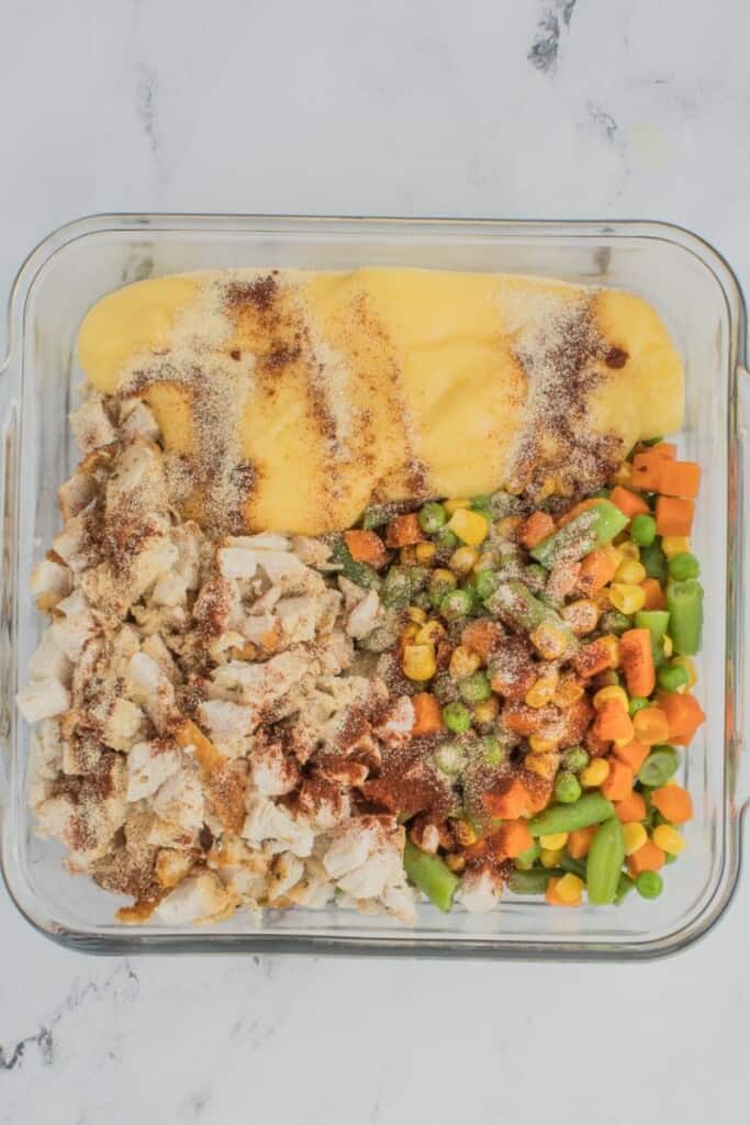 The ingredients for the filling of chicken pot pie in a square baking dish.