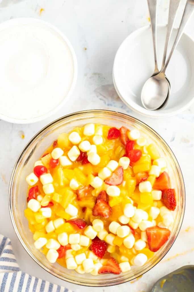 Mixing in mini marshmallows with fruit fluff salad.