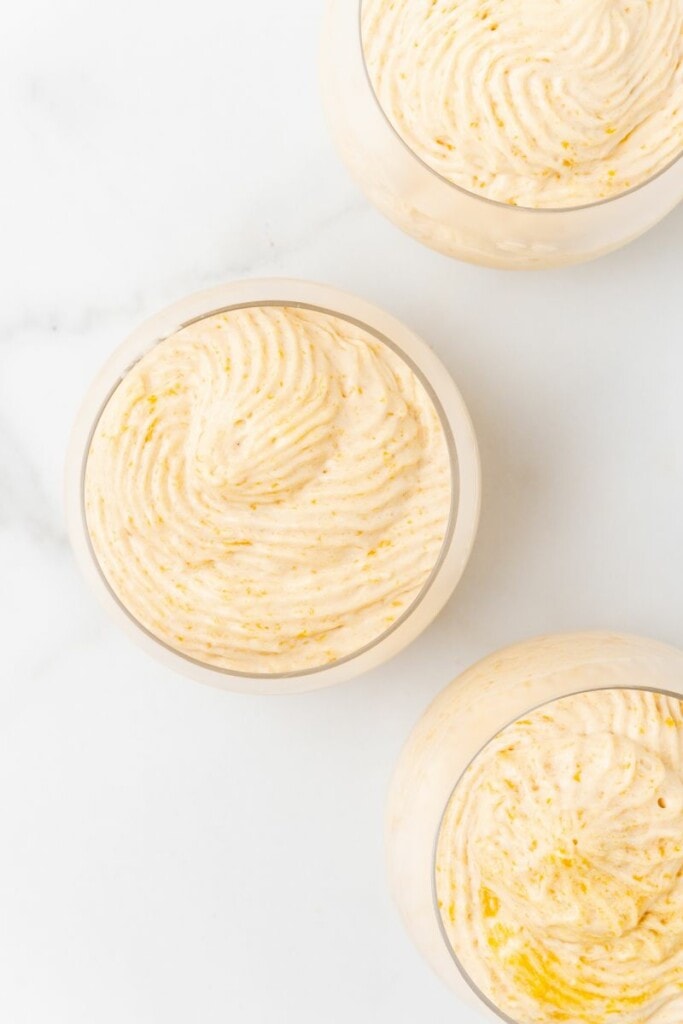 Pouring mango mousse into individual dessert serving dishes.