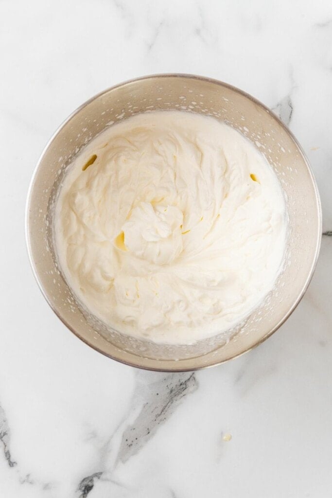 Folding mango mixture into whipped cream in a mixing bowl.