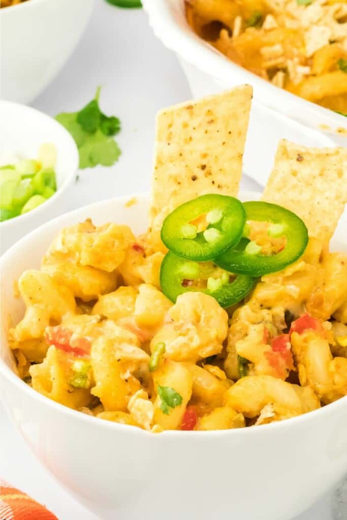 close up of mexican mac and cheese topped with tortilla chips and jalapeño peppers