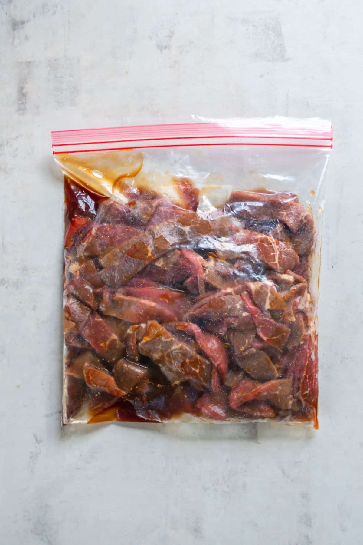 Slices of sirloin steak in a zip top bag with teriyaki sauce.