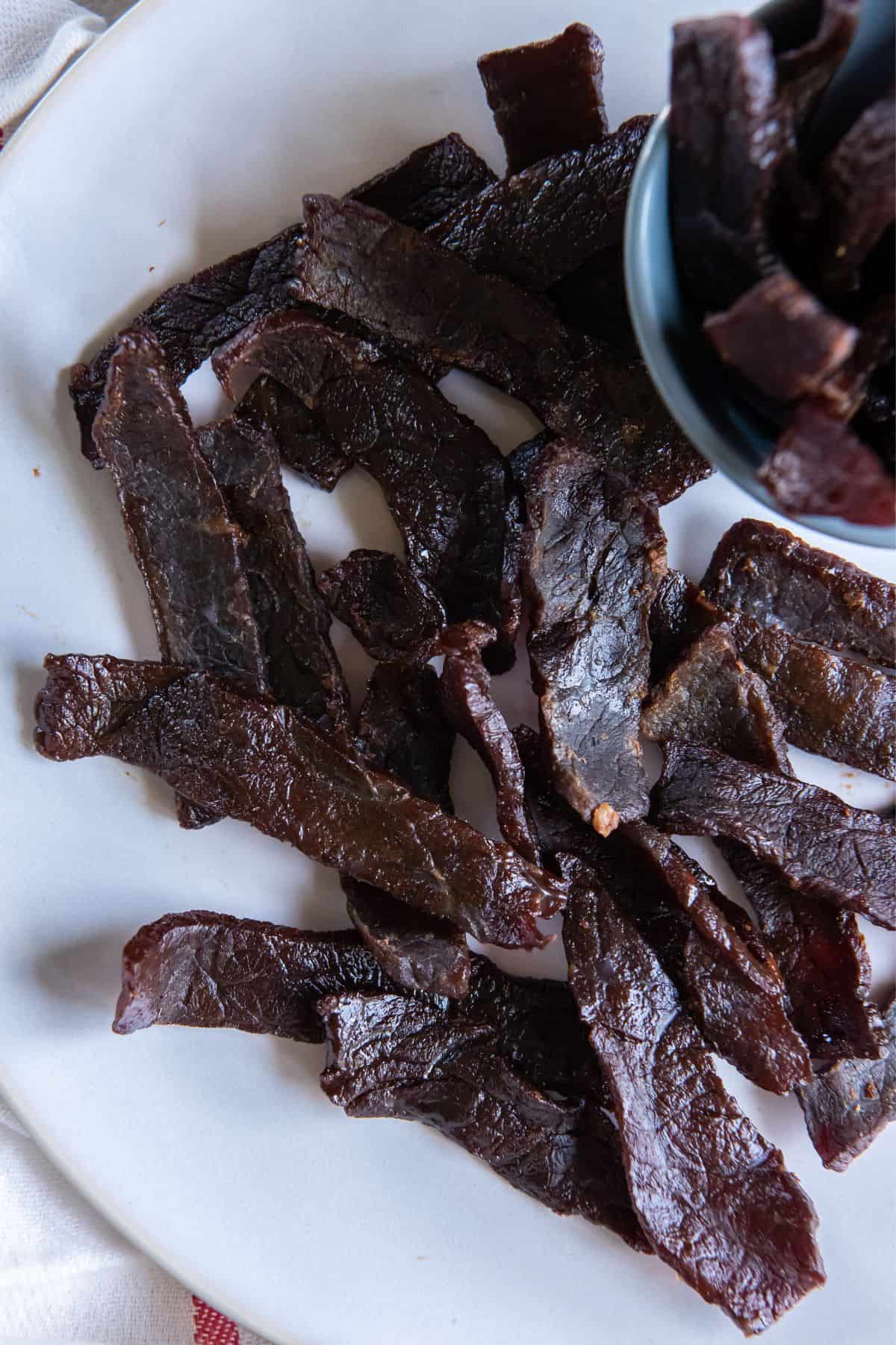 Air fryer beef jerky strips on a plate.
