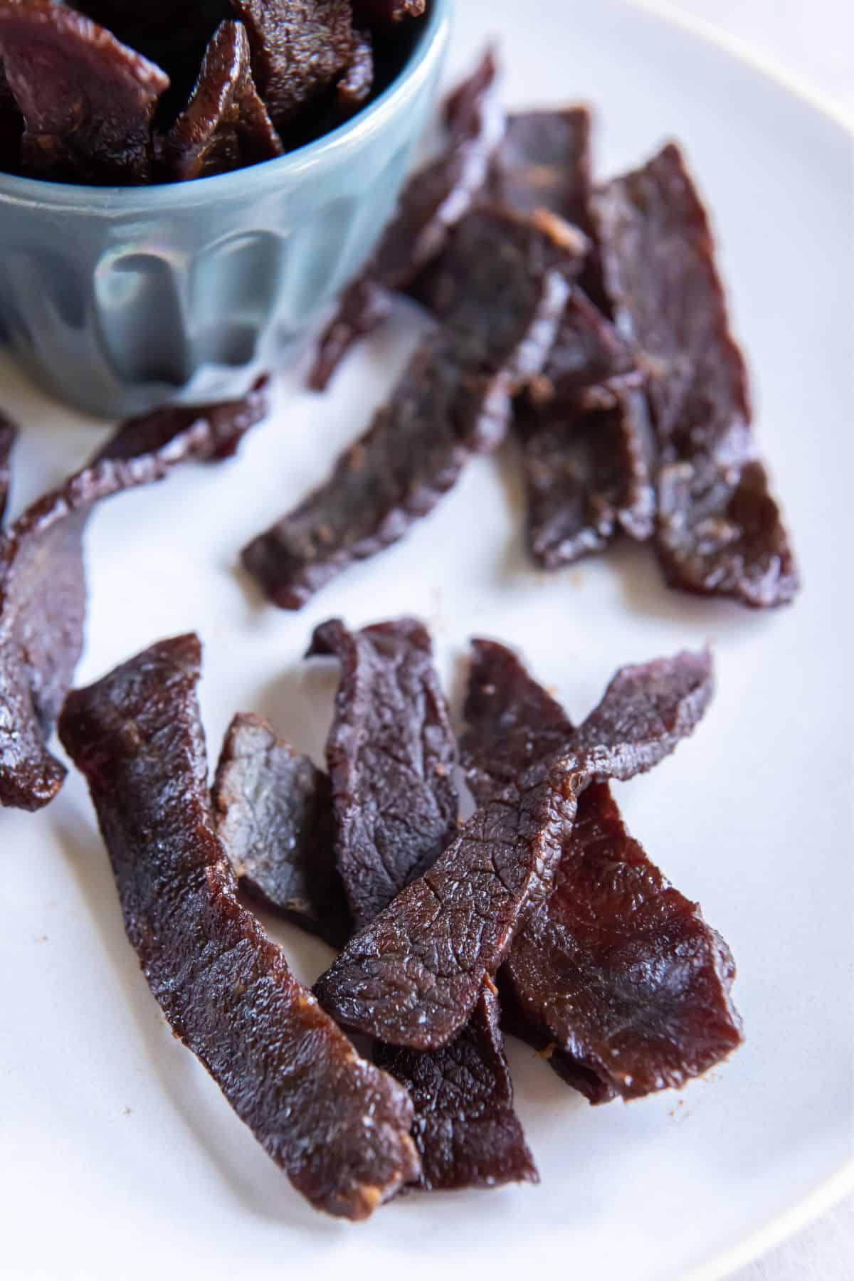 Close up of the beef jerky on a white plate.
