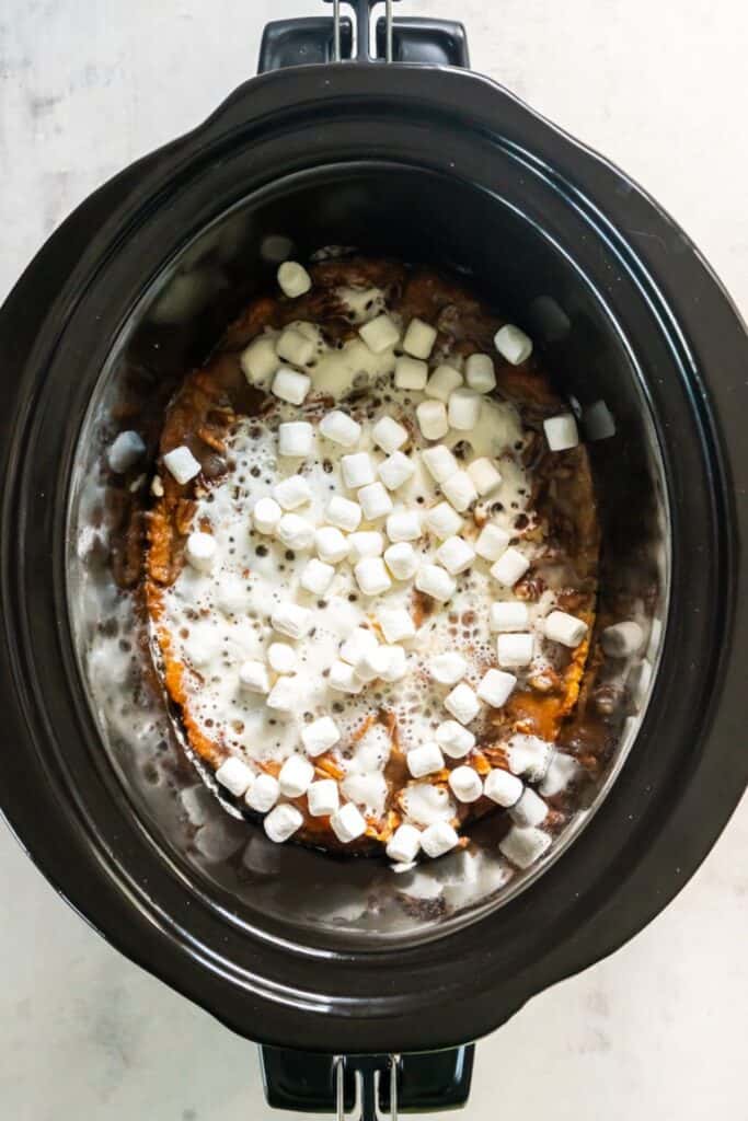 Marshmallows added on top of sweet potato casserole in a crock pot.