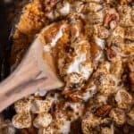 Close up of the crock pot sweet potato casserole with a wooden serving spoon in it.
