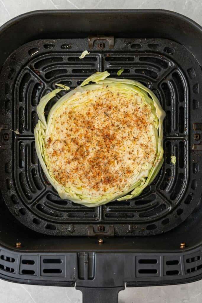 adding a slice of cabbage into the air fryer with spices