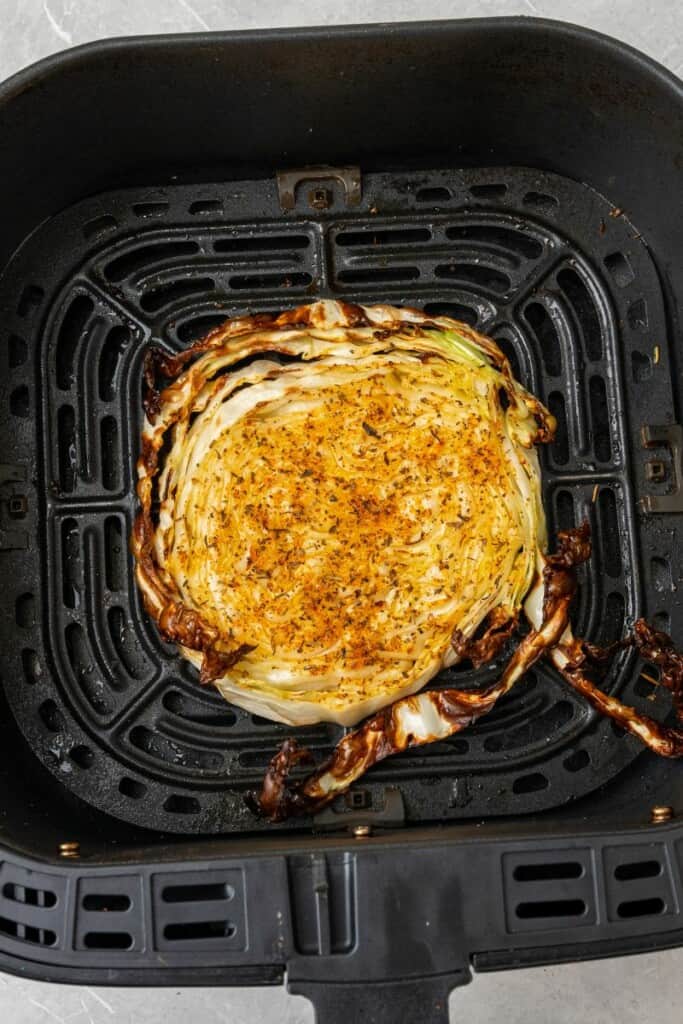 cooked seasoned cabbage steak in an air fryer basket