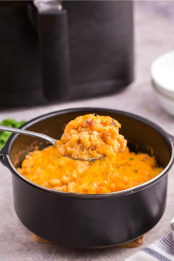 serving a scoop of air fried mac and cheese with a spoon.