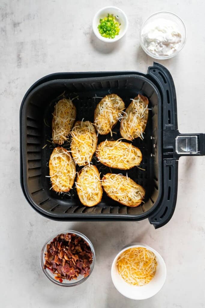adding shredded cheese to the baked potatoes.