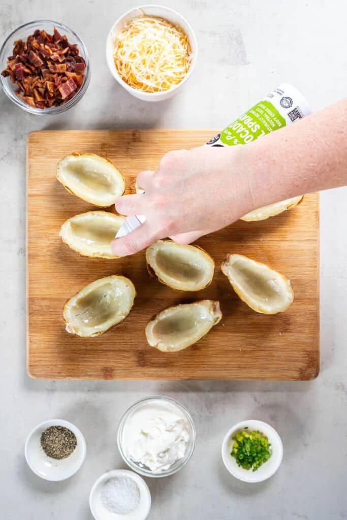 spraying the inside of the potatoes with olive oil.