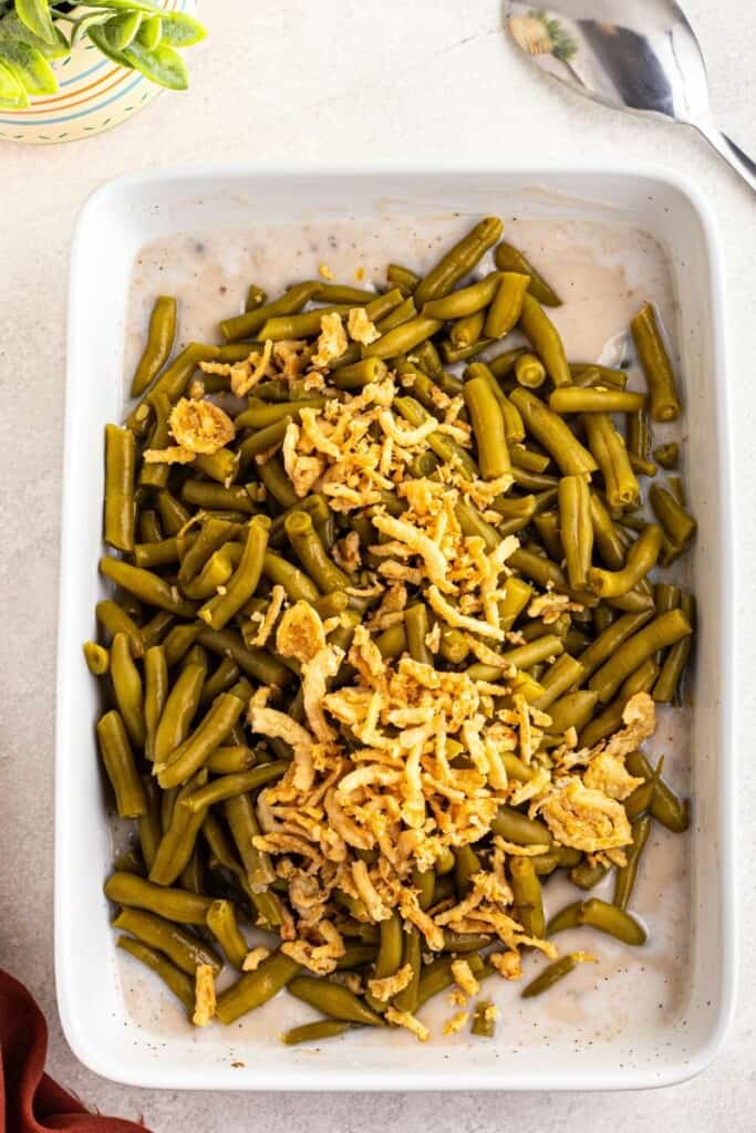 mixing together cream of mushroom soup with green beans and spices.