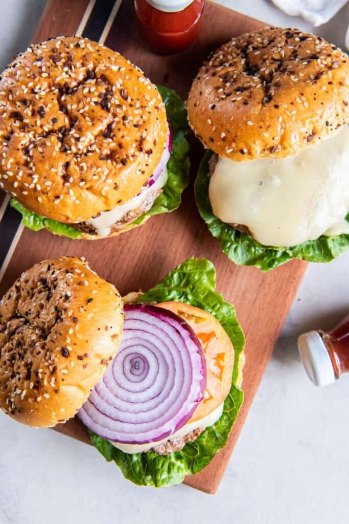 three turkey cheeseburgers with toppings and ketchup.